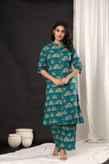 A woman modeling a teal blue and beige printed kurta set with matching pants, standing in front of a split black and white studio backdrop.