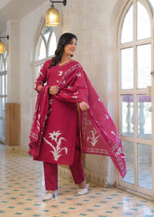 A woman models a magenta pink ethnic salwar kameez suit with white floral embroidery, consisting of a long kurta, matching trousers, and a dupatta, set against a bright, arched hallway with tiled floors.