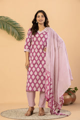 A woman models a three-piece salwar kameez suit set in a studio setting. The set features a magenta pink and white patterned kurta, matching trousers, and a coordinating printed dupatta.