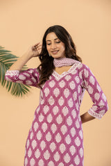 A woman modeling a magenta and white patterned kurta with a matching pink scarf, set against a solid beige background with a green palm leaf prop.