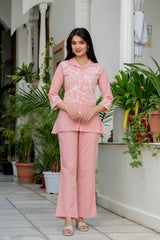 Woman in a pink traditional outfit standing in front of plants