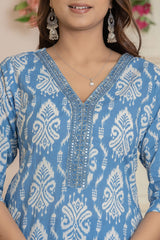 A close-up of a woman wearing a light blue and white patterned kurta with detailed silver embroidery around the V-neckline, paired with silver earrings and a necklace.