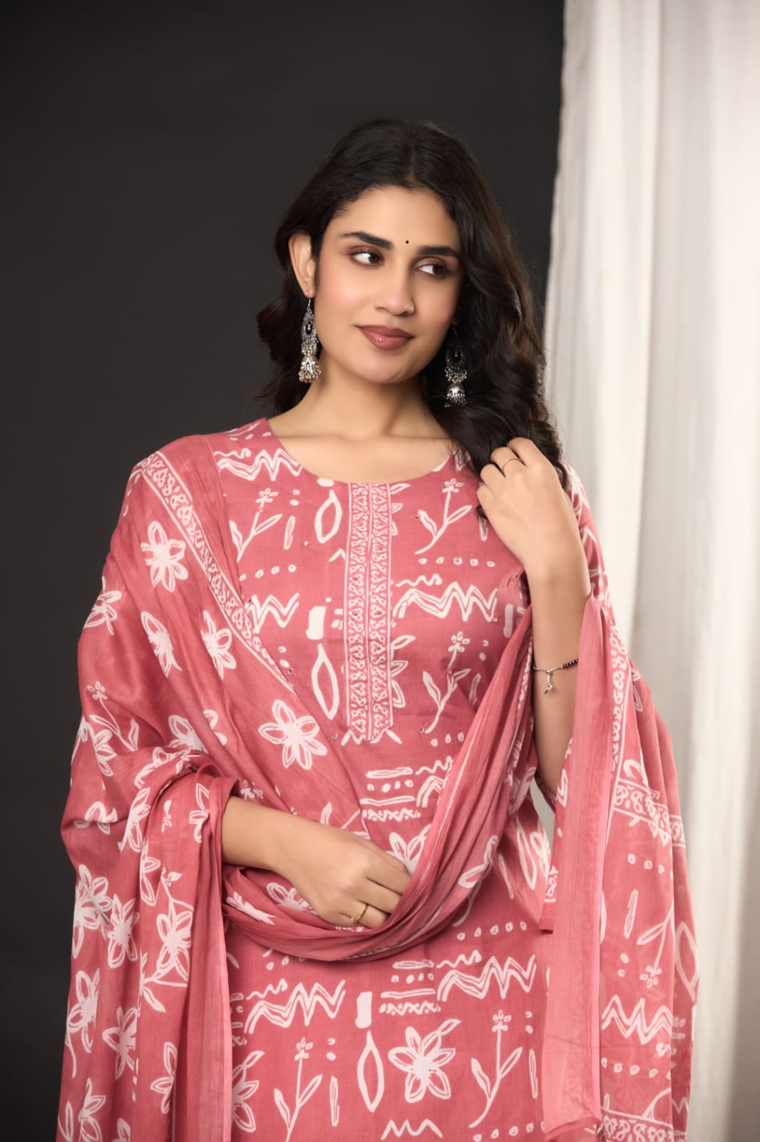"Smiling woman posing in a pink and white traditional outfit." (Includes the model's action and general color theme.)
