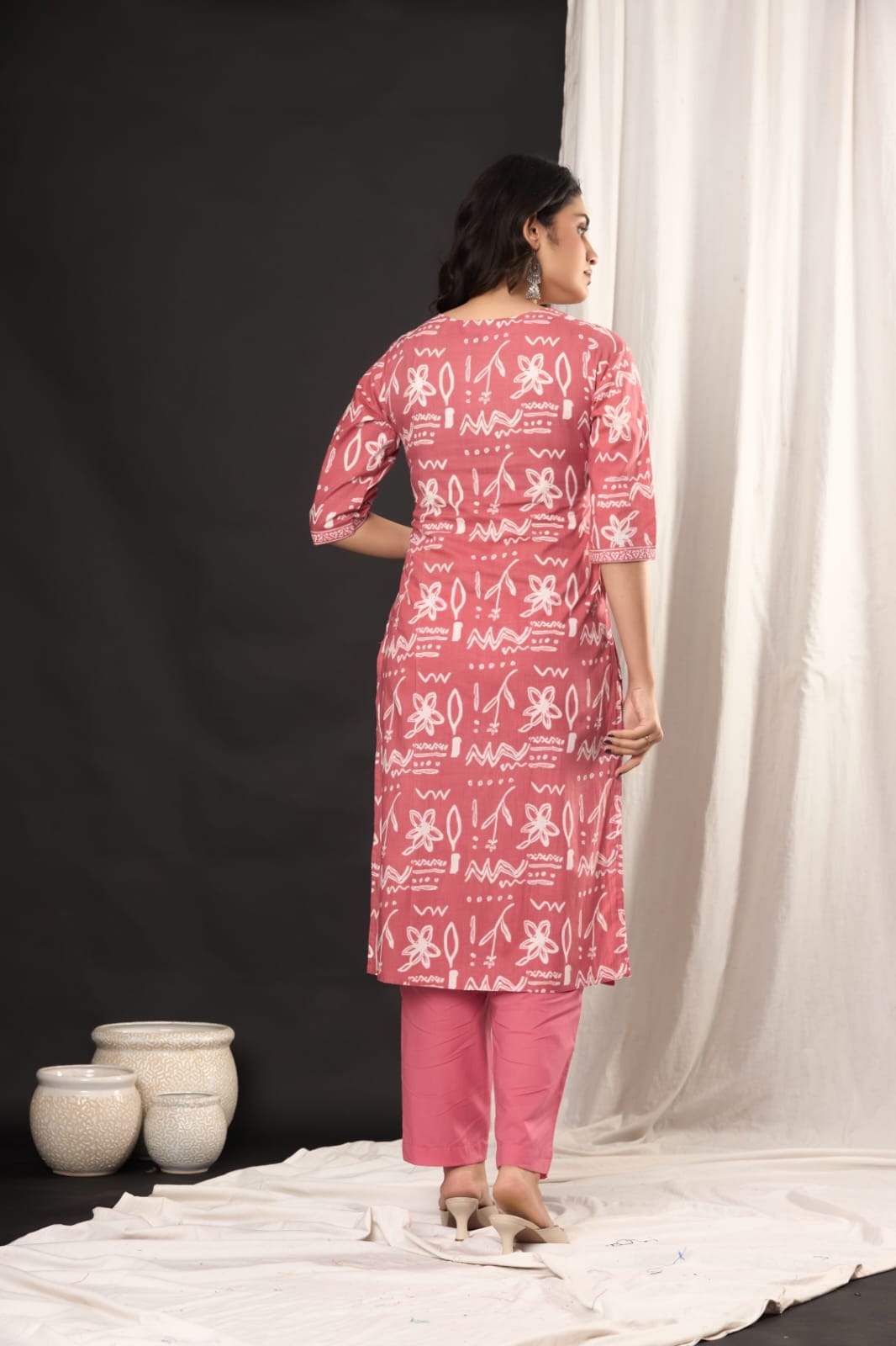 "Smiling woman posing in a pink and white traditional outfit." (Includes the model's action and general color theme.)